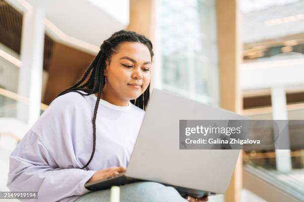 mix race girl student plus size working on laptop on stairs in modern building - resource library stock pictures, royalty-free photos & images
