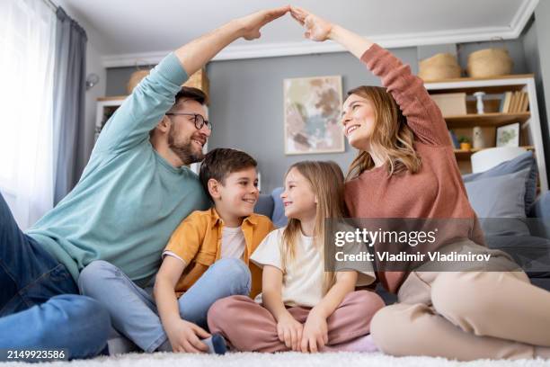 familia alegre que forma una casa con las manos - seguridad fotografías e imágenes de stock