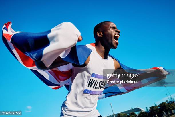 atleta eufórico con la bandera de la union jack gritando en triunfo. retrato de celebración al aire libre con cielo azul. concepto de victoria y orgullo nacional. - acontecimiento deportivo internacional fotografías e imágenes de stock