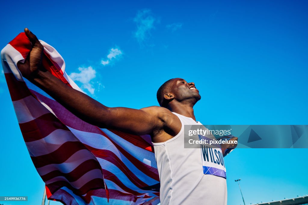 Exuberant athlete holding American flag with open arms. Sports event concept outdoor portrait. National pride and joy expression.