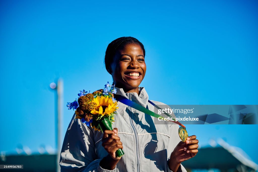 International athlete holding medal with bouquet of flowers. Outdoor portrait with architectural backdrop. Reflection on success concept