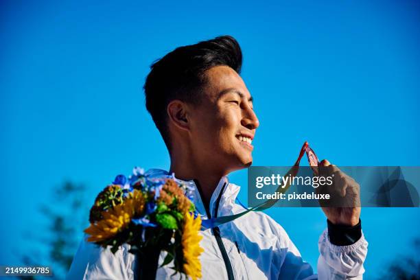 international athlete holding medal with bouquet of flowers. outdoor portrait with architectural backdrop. reflection on success concept - medalist stock pictures, royalty-free photos & images