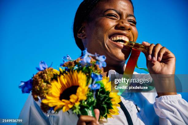 international athlete holding medal with bouquet of flowers. outdoor portrait blue backdrop. reflection on success concept - olympische spelen stockfoto's en -beelden