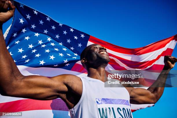 exuberant athlete standing on the podium with an american flag in the background. international sports event concept outdoor portrait. - internationales sportereignis stock-fotos und bilder