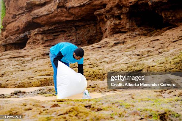 volunteer person cleaning the beach of garbage - dépollution photos et images de collection