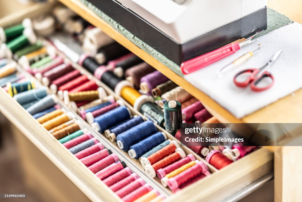Assorted colored wool, rayon and cotton thread on spools in cabinet. Material used for quilting,sewing, fiber arts, embroidery and in the textiles industry