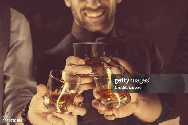 men drinking whiskey, close up of glasses and hands - man whisky stock pictures, royalty-free photos & images