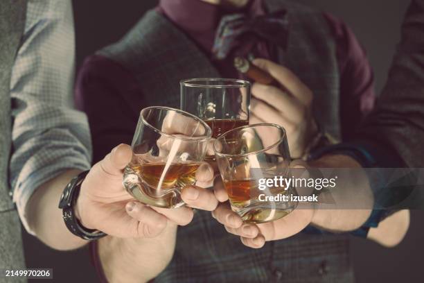 men drinking whiskey, close up of glasses and hands - gentlemens club stock pictures, royalty-free photos & images