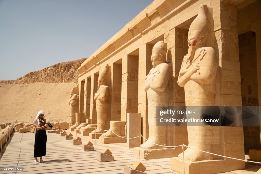 Female photographer in vacation standing with photo camera in front of the incredible Temple of Queen Hatshepsut, Luxor Egypt