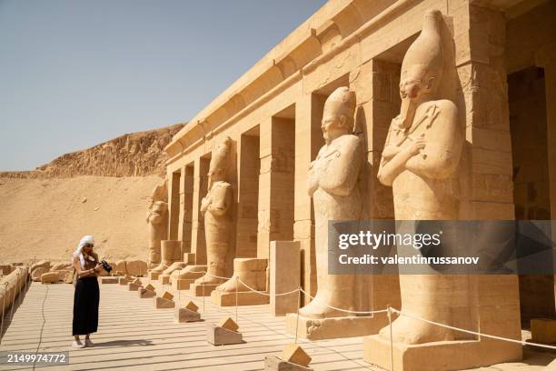 female photographer in vacation standing with photo camera in front of the incredible temple of queen hatshepsut, luxor egypt - hatshepsut stock pictures, royalty-free photos & images