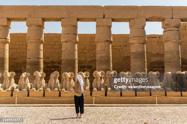 female tourist walking at the karnak temple in luxor among alley of sphinxes in thebes - sphinx in karnak temple stock pictures, royalty-free photos & images