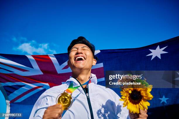 ekstatischer athlet mit medaille und sonnenblumenstrauß vor der australischen flagge. freudige siegesfeier im außenporträt. nationales stolz- und leistungskonzept. - internationales sportereignis stock-fotos und bilder
