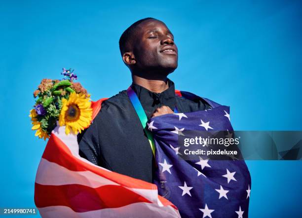 stolzer sportler in die flagge der usa gehüllt. feierporträt im freien mit blauem himmelshintergrund. sportliches sieg- und glückskonzept. - fairness stock-fotos und bilder