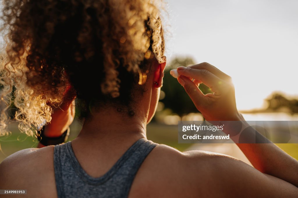 Fitness-Läuferin setzt Kopfhörer auf