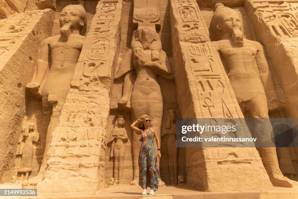 woman standing in front of the temple of hathor and nefertari, dedicated to the goddess hathor and ramesses ii's queen, nefertari, at abu simbel, egypt - aswan stock pictures, royalty-free photos & images
