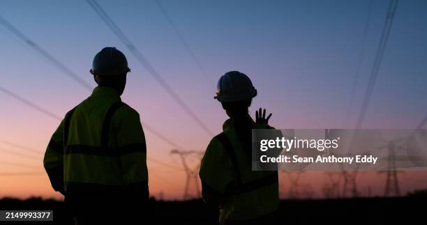 power lines, planning and business people at sunset for electricity, circuit and voltage infrastructure. engineering, teamwork and silhouette of technicians with wires, grid and cable maintenance - hoogspanningsmast stockfoto's en -beelden