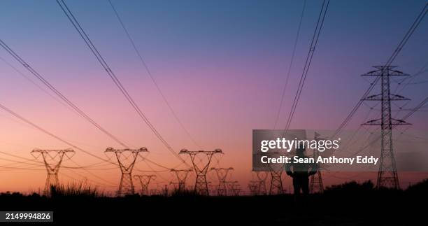 power lines, thinking and silhouette of person at sunset for electricity, circuit cables and voltage wires. engineering, construction and technician for maintenance, infrastructure and installation - electricity stockfoto's en -beelden