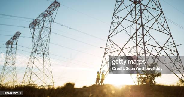 personas, ingenieros y torre de transmisión para líneas eléctricas o ingeniería industrial, tensión o infraestructura. puesta de sol, pilón y poste o cables con cielo azul para circuito, corriente o conexión - producción de combustible y energía fotografías e imágenes de stock