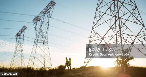 people, engineer and transmission tower or industrial with electricity for maintenance, voltage or infrastructure. sunset, pylon and pole or cables with blue sky for circuit, current or connection - electricity stockfoto's en -beelden