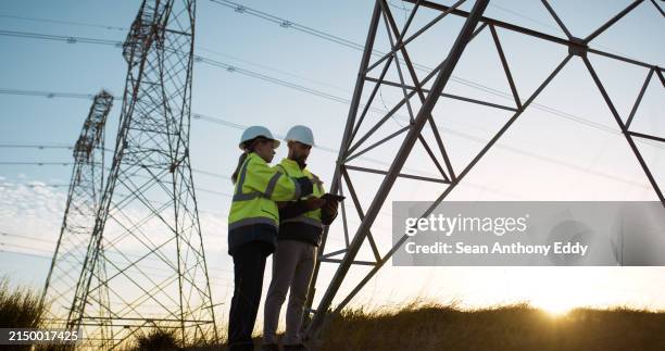 trabalho em equipe, engenheiro eletricista e tablet em usina com inspeção para transmissão de energia elétrica ou verificação de torre. engenharia, colaboração ou transferência de dados para distribuição ou manutenção de energia - torre estrutura construída - fotografias e filmes do acervo