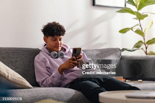 Teenage Boy with Smartphone Relaxing on Living Room Sofa Teenage Boy with Smartphone Relaxing on Living Room Sofa