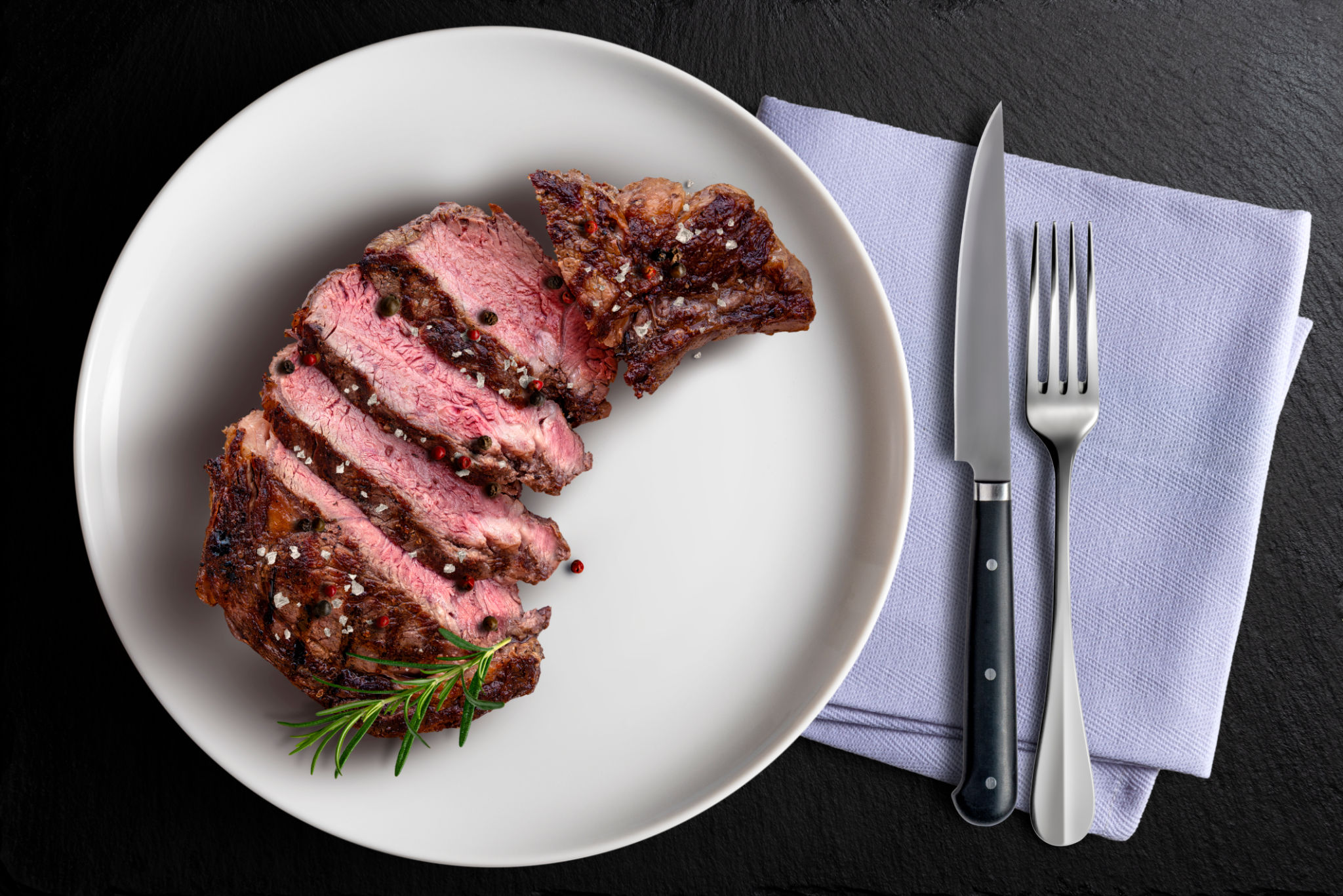Top view of sliced Rib eye beef in white round plate flavored with knife and fork Top view of sliced Rib eye beef in white round plate flavored with knife and fork