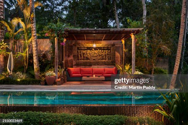 pergola with sitting area next to pool at luxury villa, situated in garden with tropical plants at dusk - pergola bois photos et images de collection
