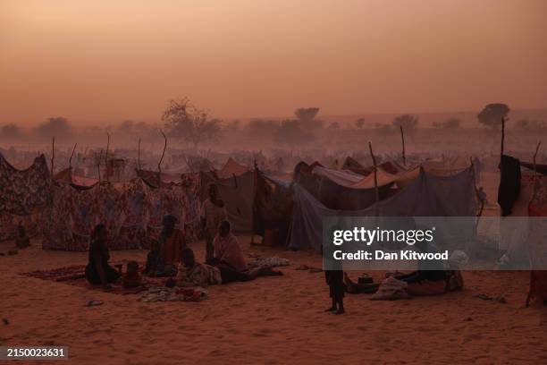 Newly arrived Sudanese refugees sit outside their makeshift shelters at twilight close to a relocation camp on April 24, 2024 near Adre, Chad. Since...