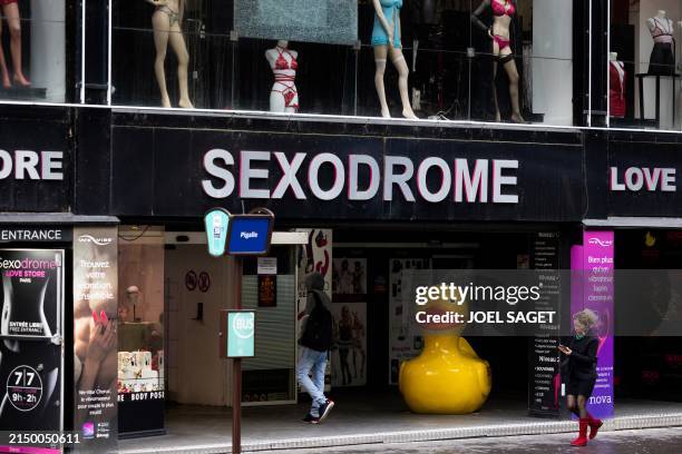 Passerby walks past sex shops near Place Pigalle in Paris on April 28, 2024.