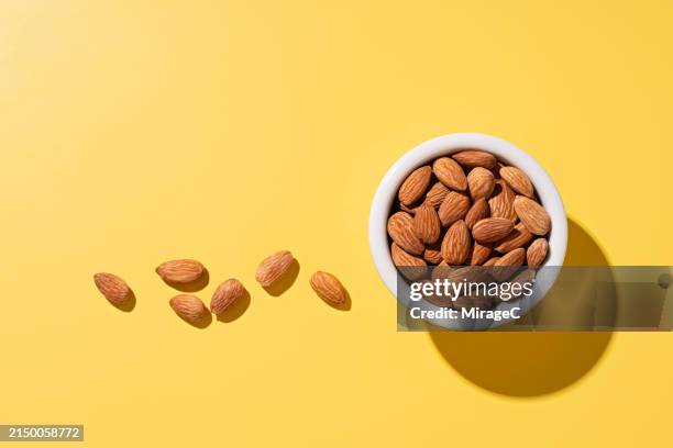 almonds in a bowl on yellow background - mandel bildbanksfoton och bilder