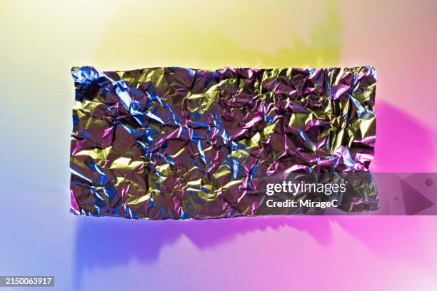 wrinkled aluminum foil with multi colored light - desigual con textura fotografías e imágenes de stock