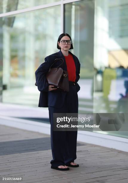 Maria Barteczko seen wearing Victoria Beckham black oversized Aviator optical glasses, H&M gold hoop earrings, Arket red wool knit sweater, Studio...