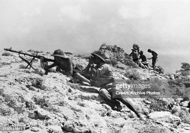 An MG34 light machine gun section from an infantry unit of the German Afrika Korps wearing the tropical issue DAK Tropenhelm pith helmet take up...