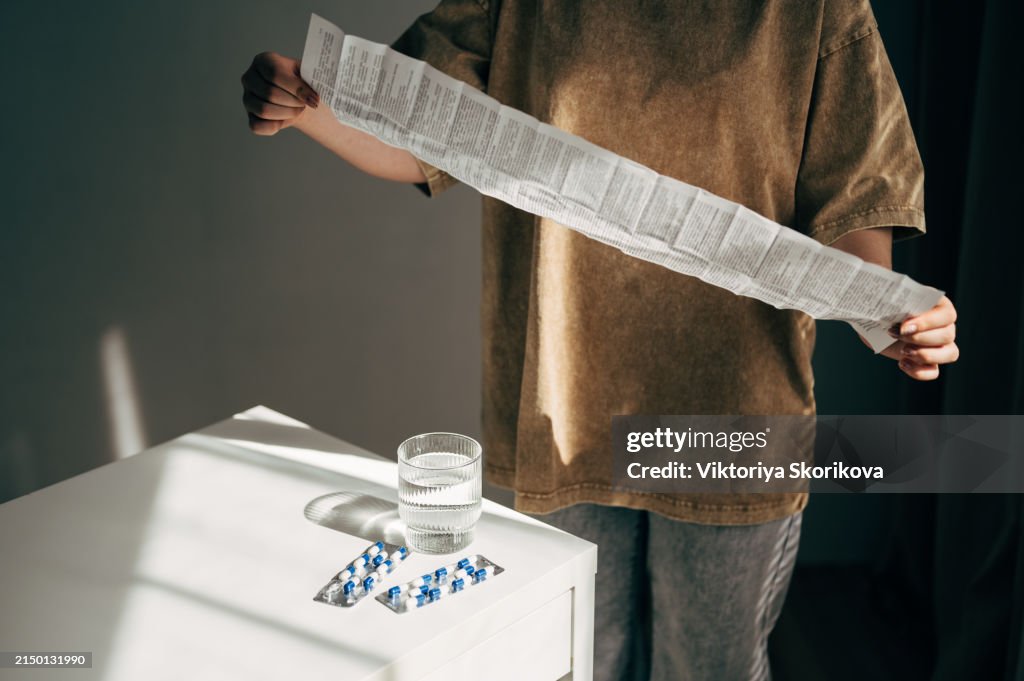 Woman Taking Medicine. Beautiful Young Female Holding Blister Pack With Pills In Hand And Reading Medical Instructions. Attractive Girl Looking At Instruction, Holding Pill Package. High Resolution