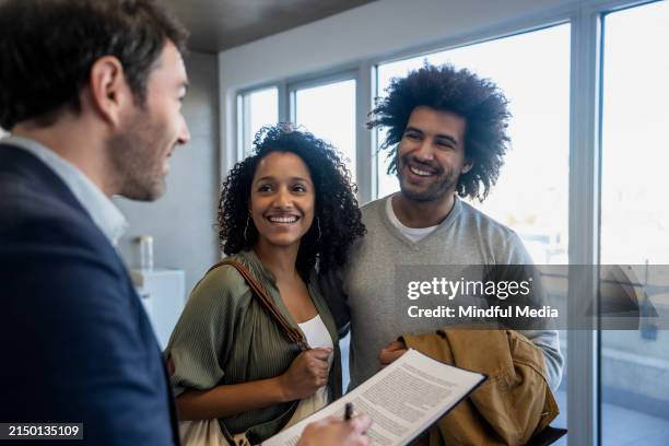 un agent immobilier fait visiter un appartement vide à un jeune couple - annonce immobilière photos et images de collection