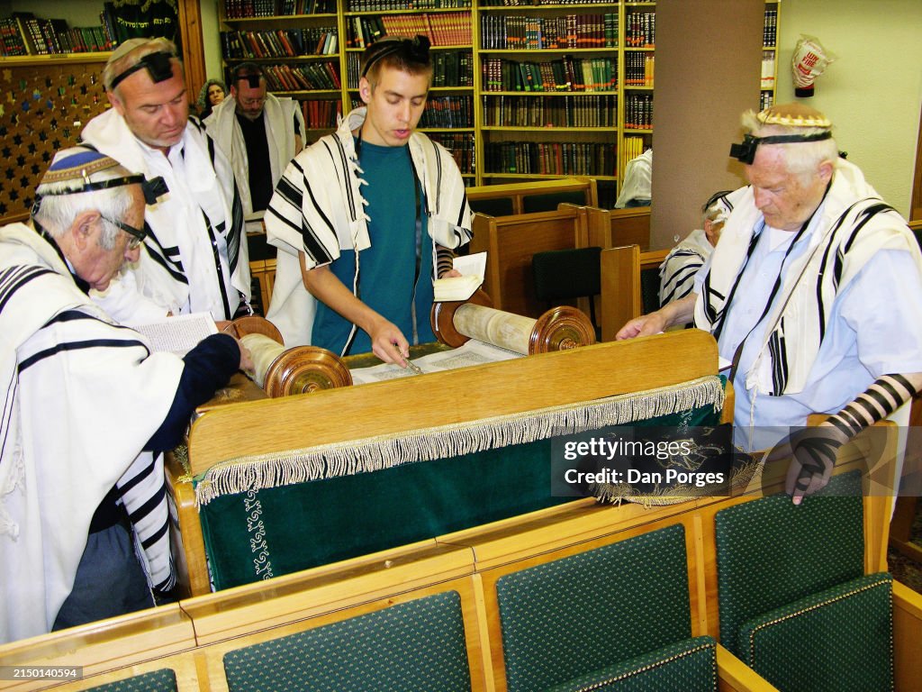 Flanked by three men, an unidentified teenager reads from the Torah ...