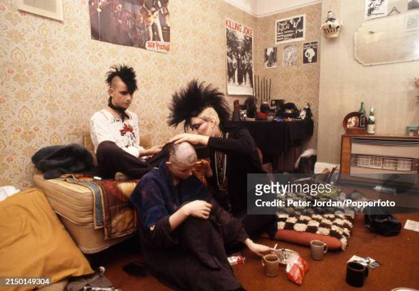 Punk having her head shaved in a bed-sit in London, circa 1983. On the wall are posters of Punk bands, the Sex Pistols and Killing Joke.