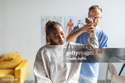Physical therapist helping young black woman with her shoulders Physical therapist helping young black woman with her shoulders