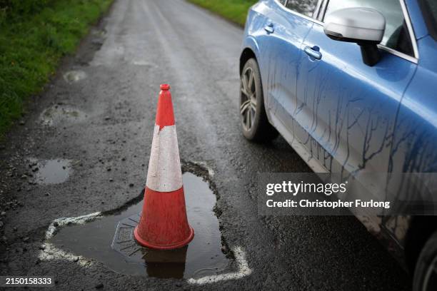 Traffic cone warns drivers of a pothole on the road on April 25, 2024 near Northwich, United Kingdom. The UK's roads have a large number of potholes...