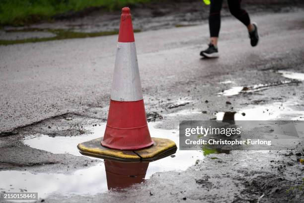 Traffic cone warns drivers of a pothole on the road on April 25, 2024 near Northwich, United Kingdom. The UK's roads have a large number of potholes...
