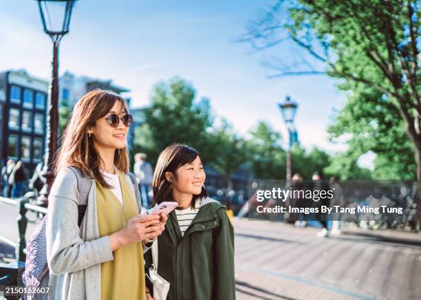 city navigation: young asian mom and her teenage daughter using mobile app for navigation and finding location while exploring in a new city - internet surfen stockfoto's en -beelden