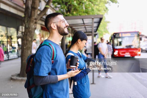 smiling medical workers waiting for their bus - waiting stock pictures, royalty-free photos & images