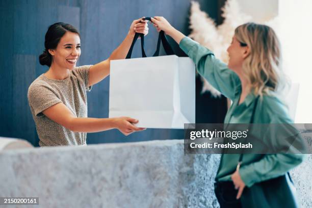 échange amical entre femmes avec un sac à provisions - sac photos et images de collection