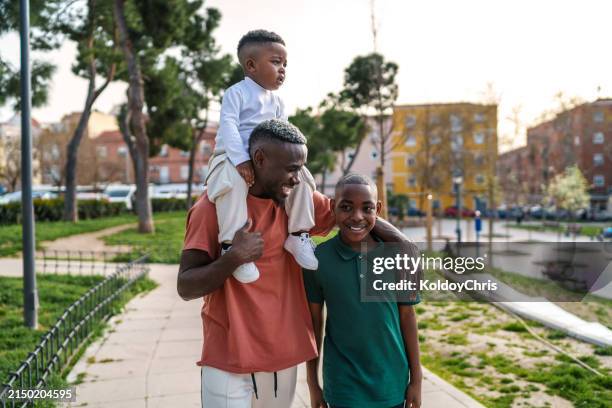 african father and sons enjoying quality time in evening park light - peel park stock pictures, royalty-free photos & images