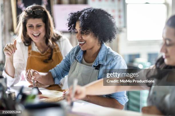 female art studio instructor laughing with students - handgemacht stock-fotos und bilder