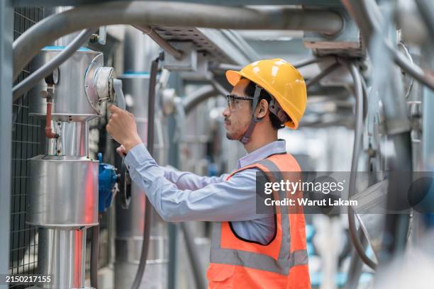 focused engineer adjusting machinery in industrial plant - compresor de aire fotografías e imágenes de stock
