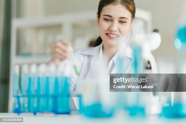 scientist evaluating green sample in test tube - weißer mantel stock-fotos und bilder