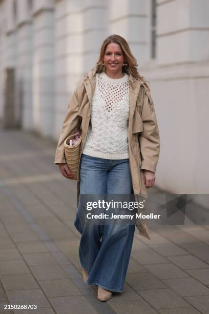 Andrea Maria S. Seen wearing gold earrings, creamy white wool cable knit sweater, blue denim wide leg jeans pants, beige oversized hooded trenchcoat...