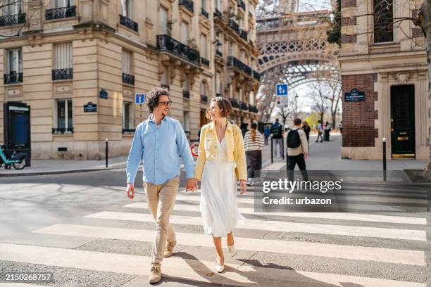 young couple crossing the street in front of an eiffel tower in paris in france - couple crossing street stock pictures, royalty-free photos & images