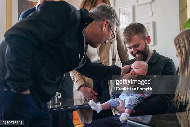 Keir Starmer, Leader of the Labour Party reacts with a 4-month old baby as he speaks with families during a visit to the Influence Cafe and Bistro in...
